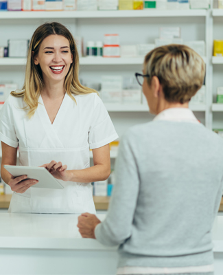 Male pharmacist selling medications at drugstore to a senior woman customer